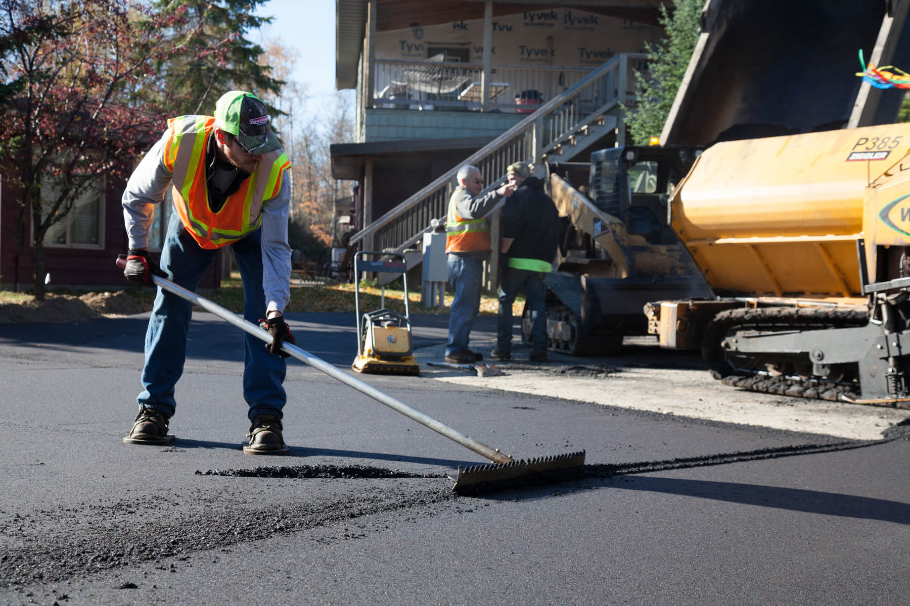 Employee raking fresh asphalt