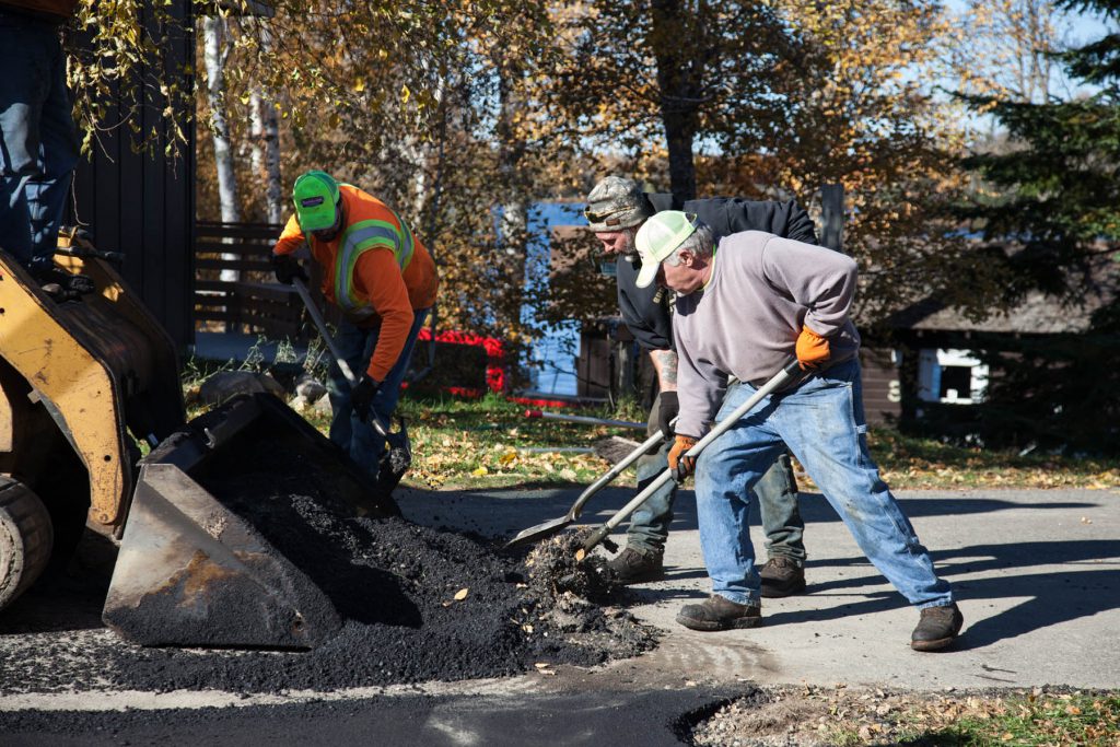 Employees raking fresh asphalt on a driveway