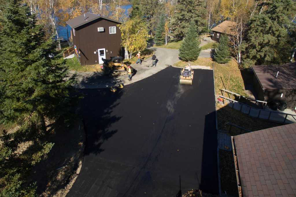 Birds-eye view of fresh pavement being steamrolled in residential driveway