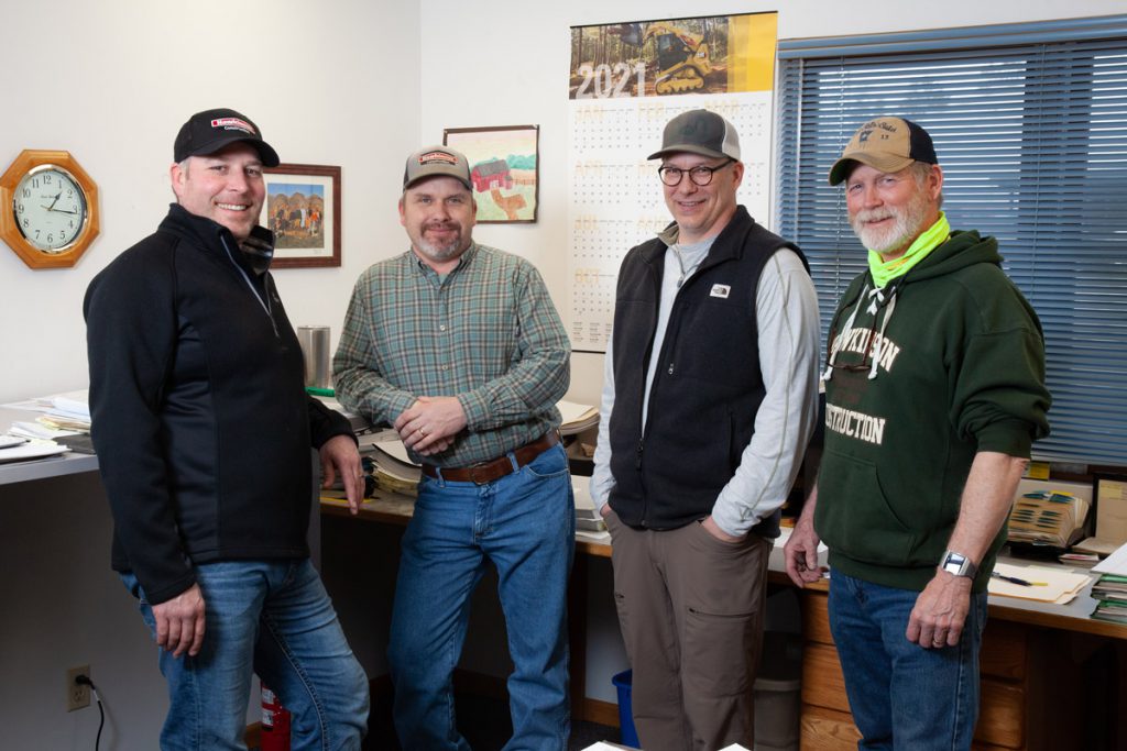 Four staff from the Hawkinson Construction team posing in an office